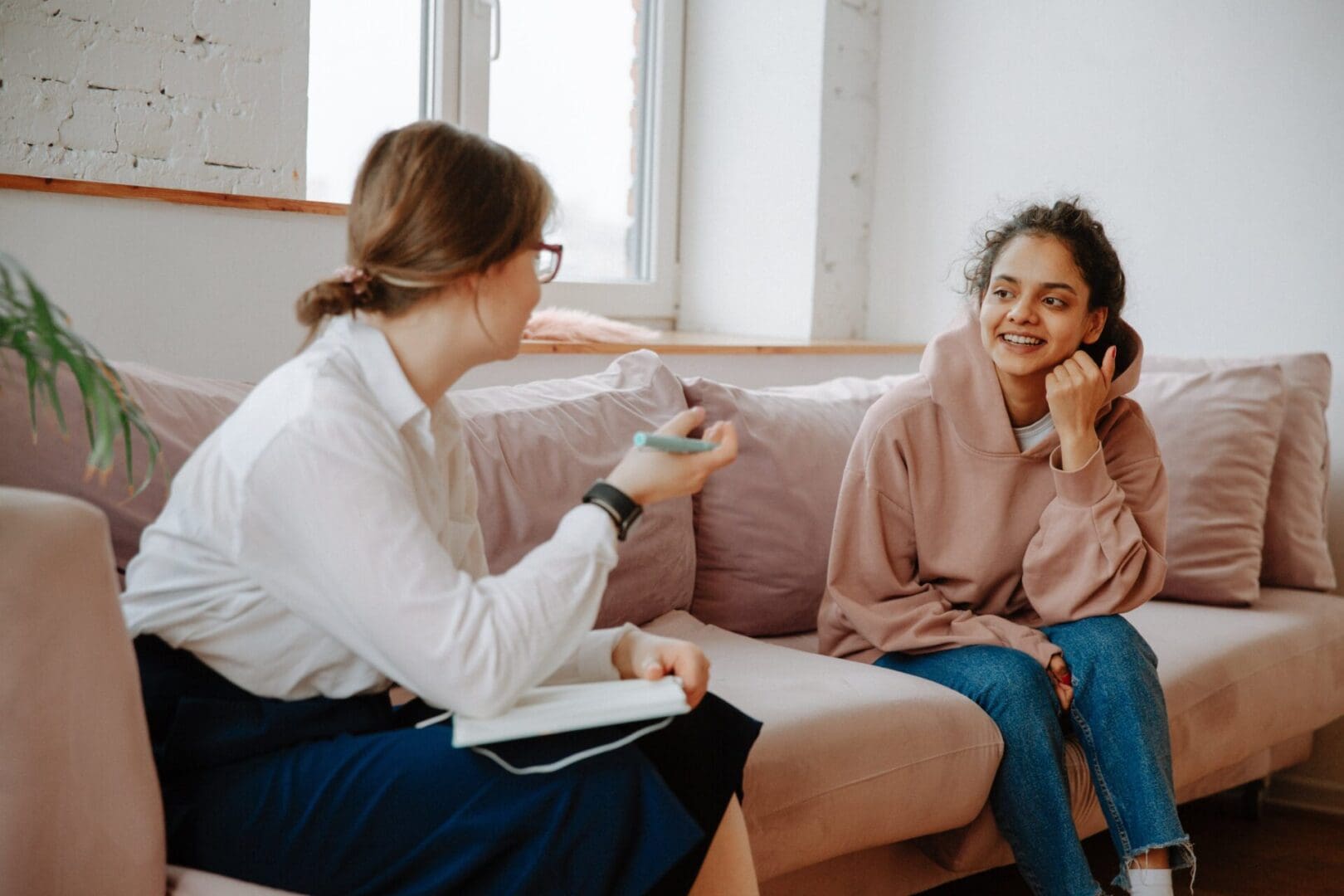 A woman sitting on top of a couch talking to another person.